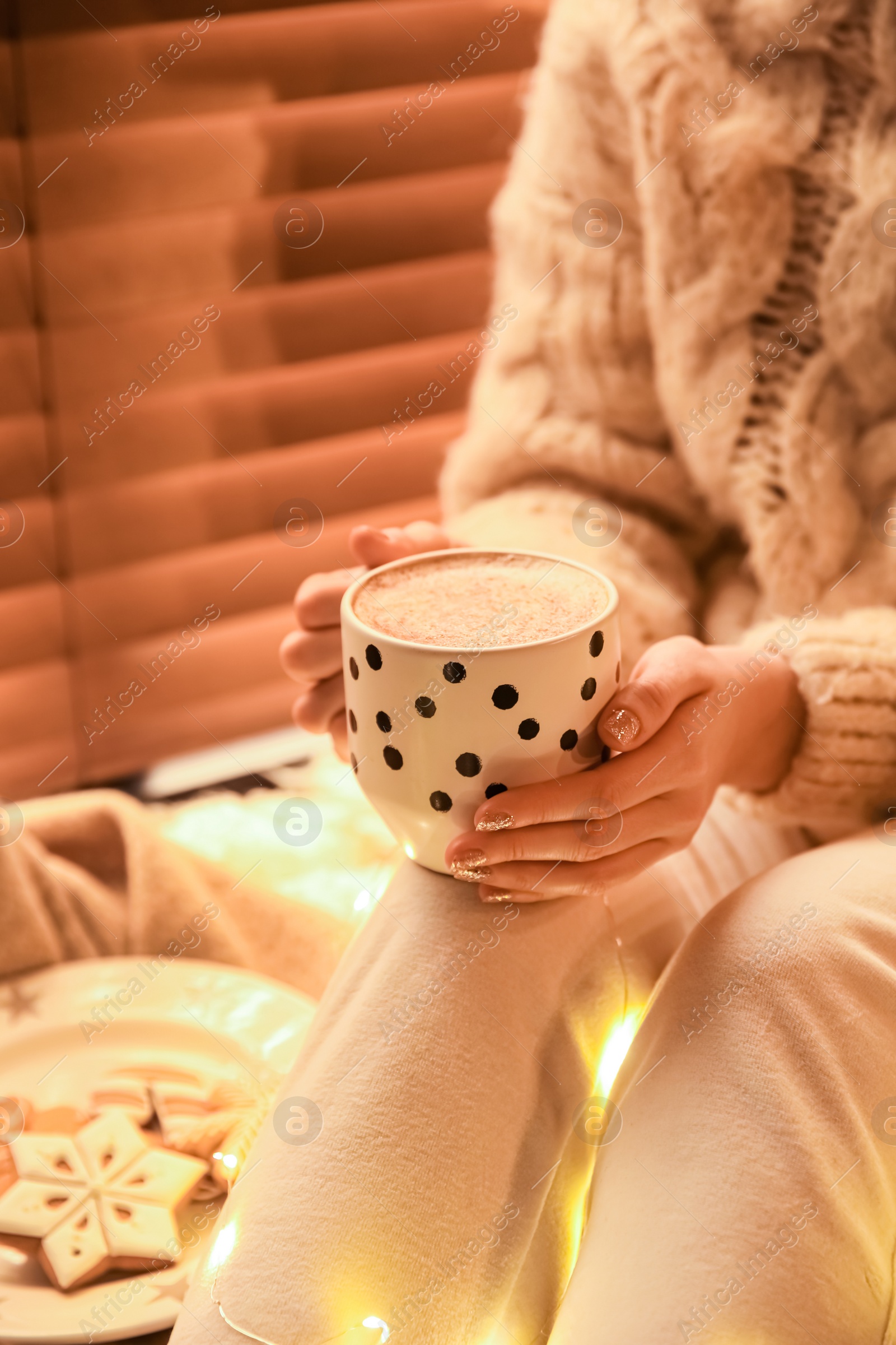 Photo of Woman with cup of hot drink and Christmas cookies at home, closeup