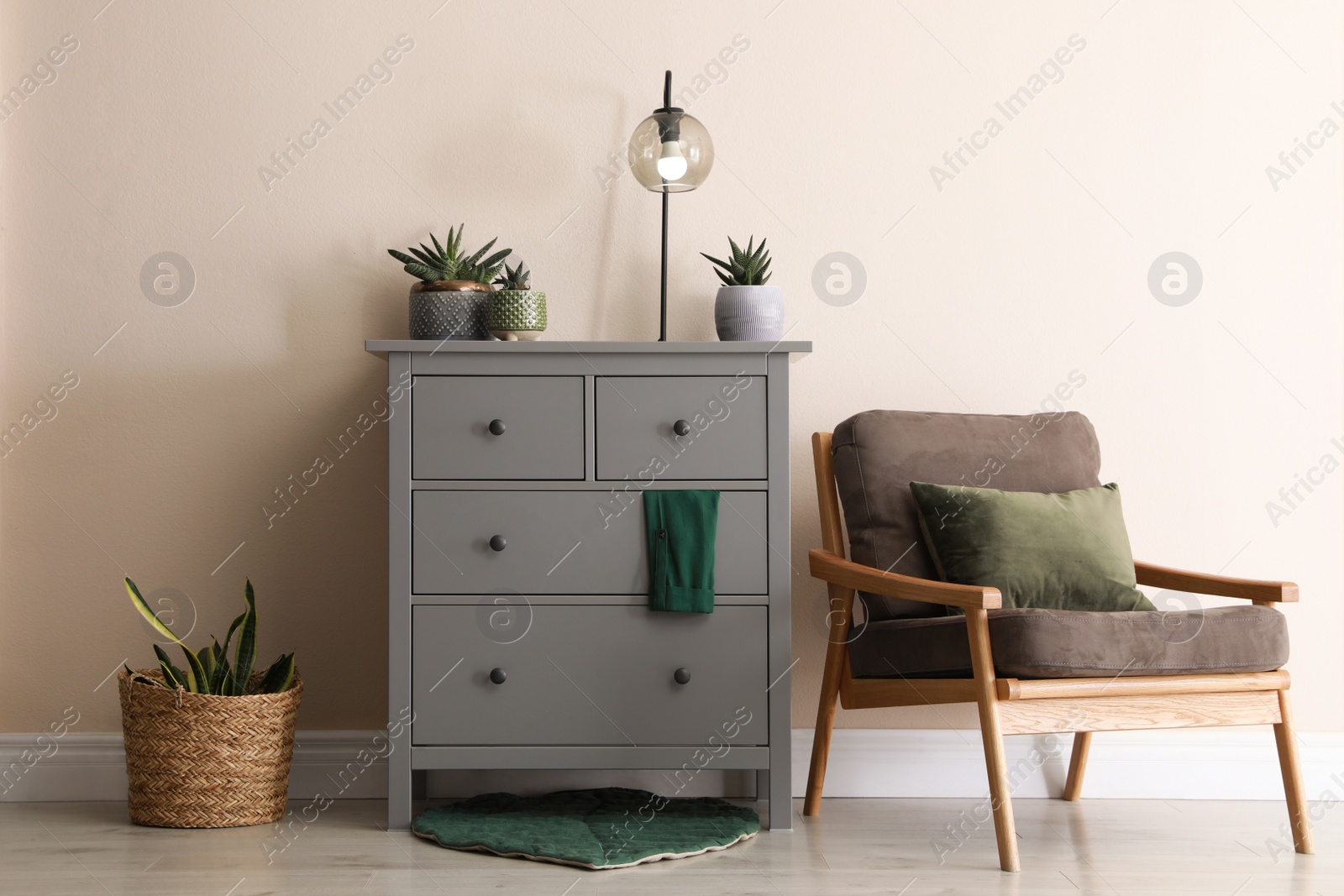 Photo of Room interior with grey chest of drawers near beige wall