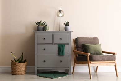 Room interior with grey chest of drawers near beige wall