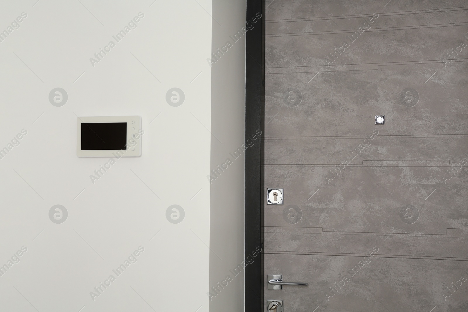 Photo of Modern video intercom on white wall near door