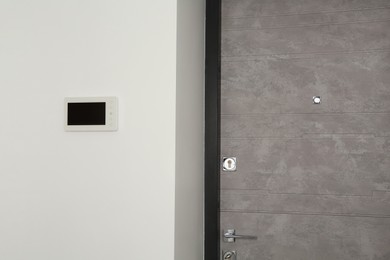 Photo of Modern video intercom on white wall near door