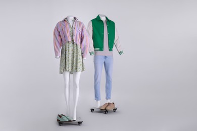 Photo of Male and female mannequins dressed in stylish outfits on grey background. Space for text