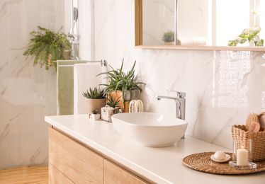 Stylish bathroom interior with countertop, mirror and houseplants. Design idea