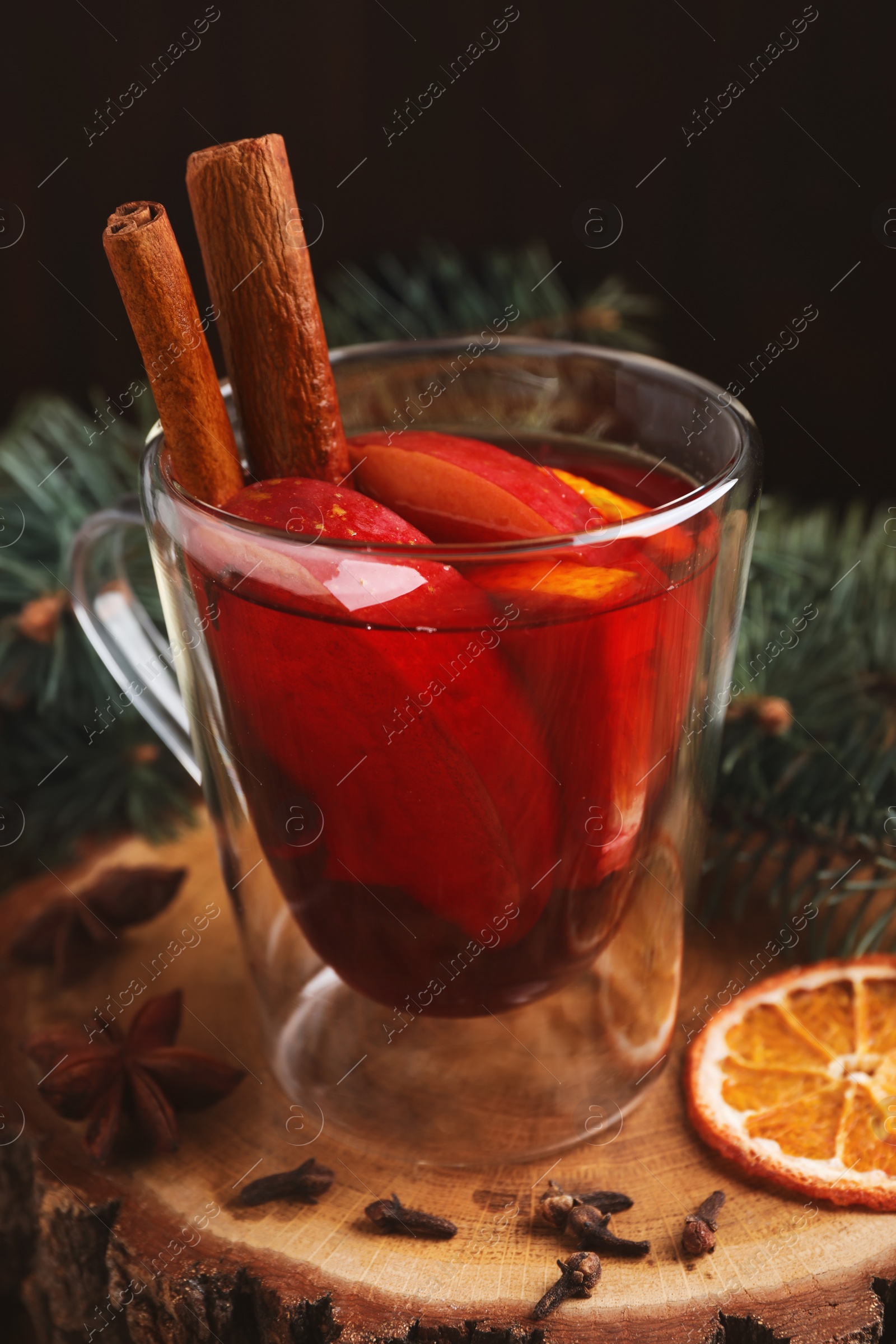 Photo of Tasty aromatic mulled wine on wooden stump, closeup