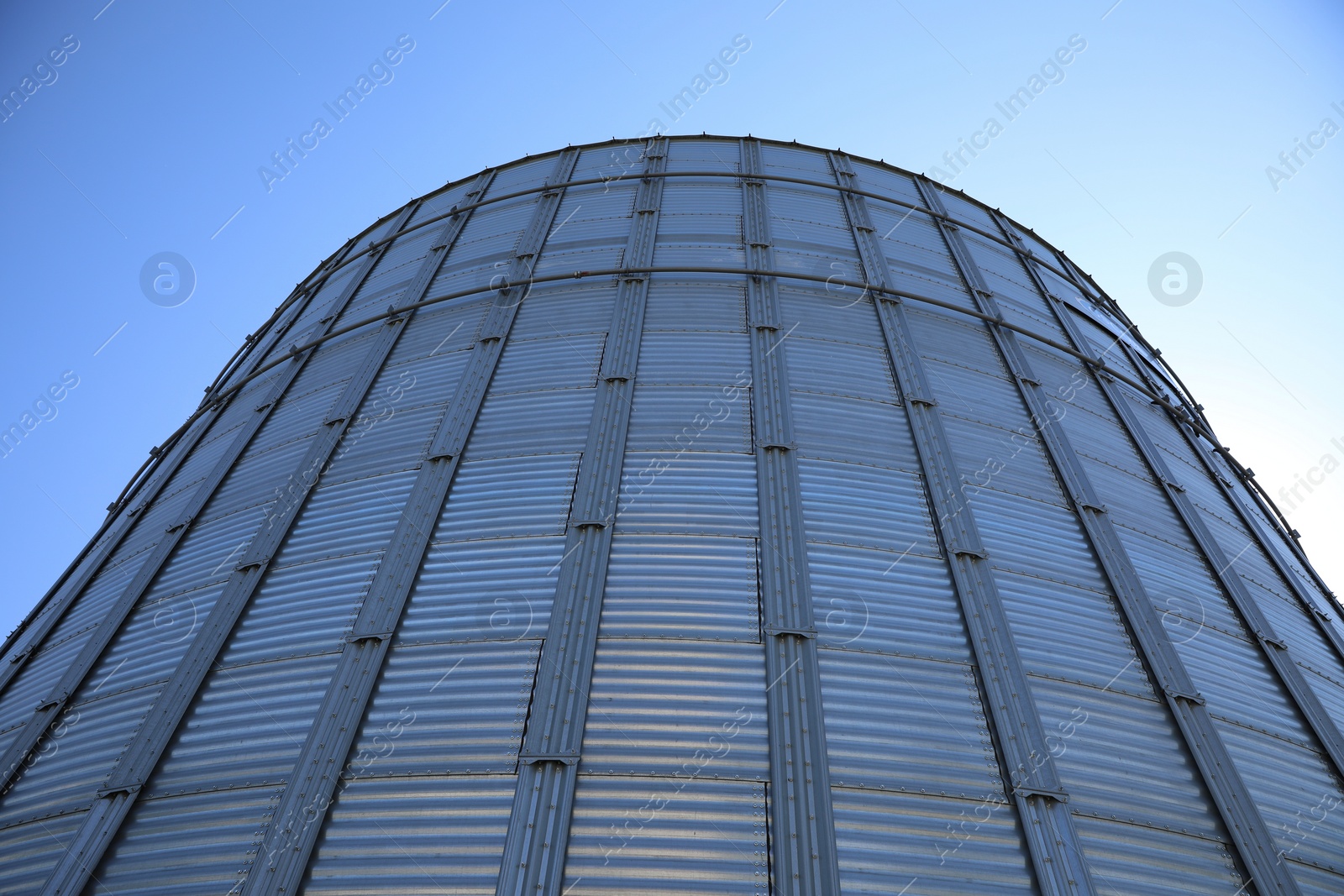 Photo of Modern granary for storing cereal grains against blue sky, low angle view