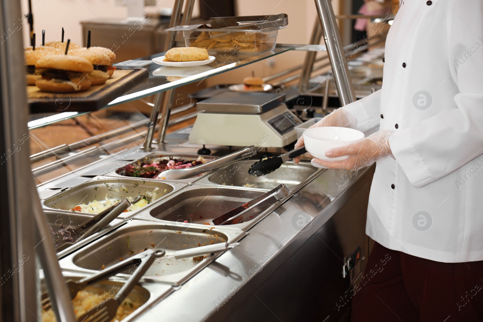 Photo of School canteen worker at serving line, closeup. Tasty food