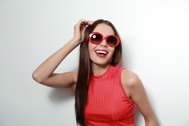 Photo of Beautiful woman in stylish sunglasses on light background