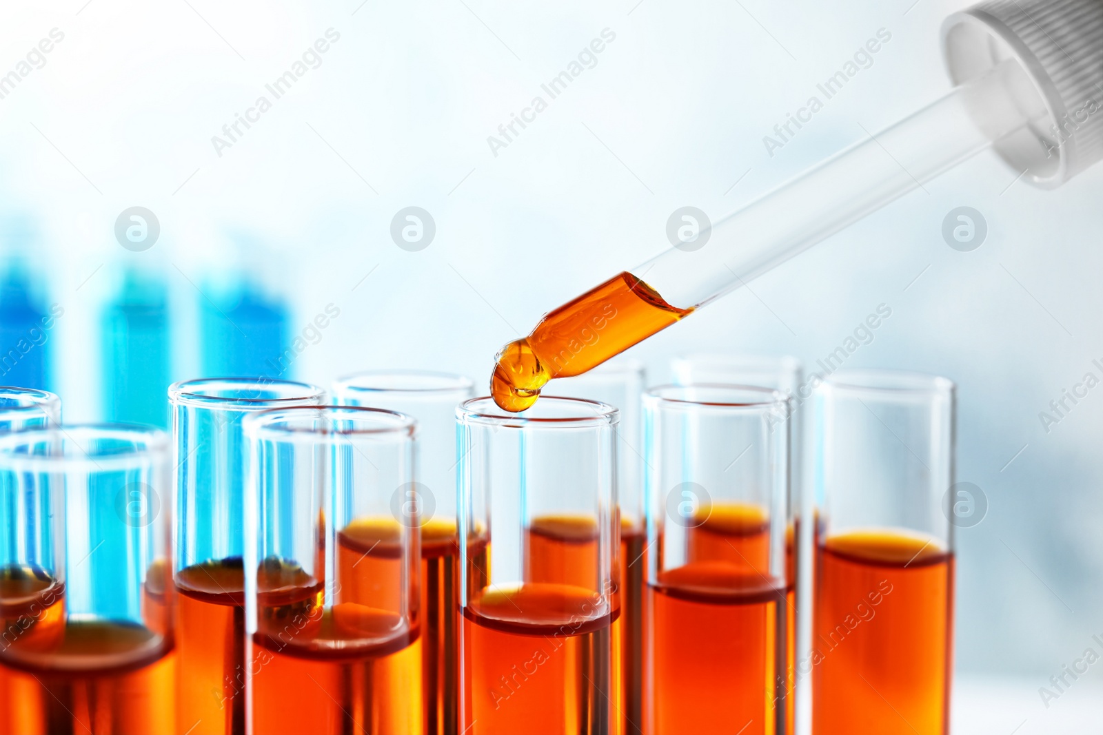 Photo of Dropping sample into test tube with orange liquid, closeup