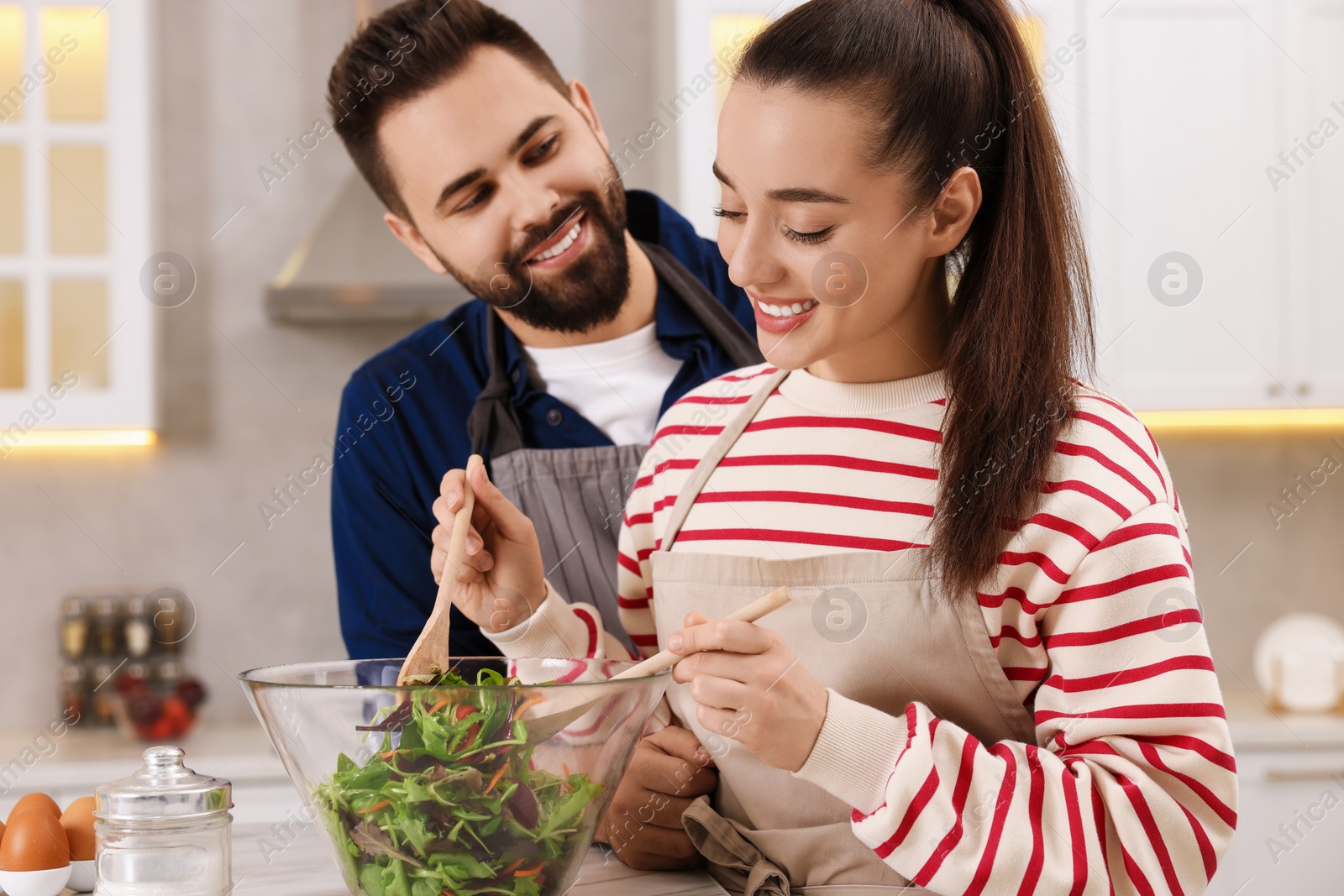 Photo of Happy affectionate couple cooking together at white table in kitchen