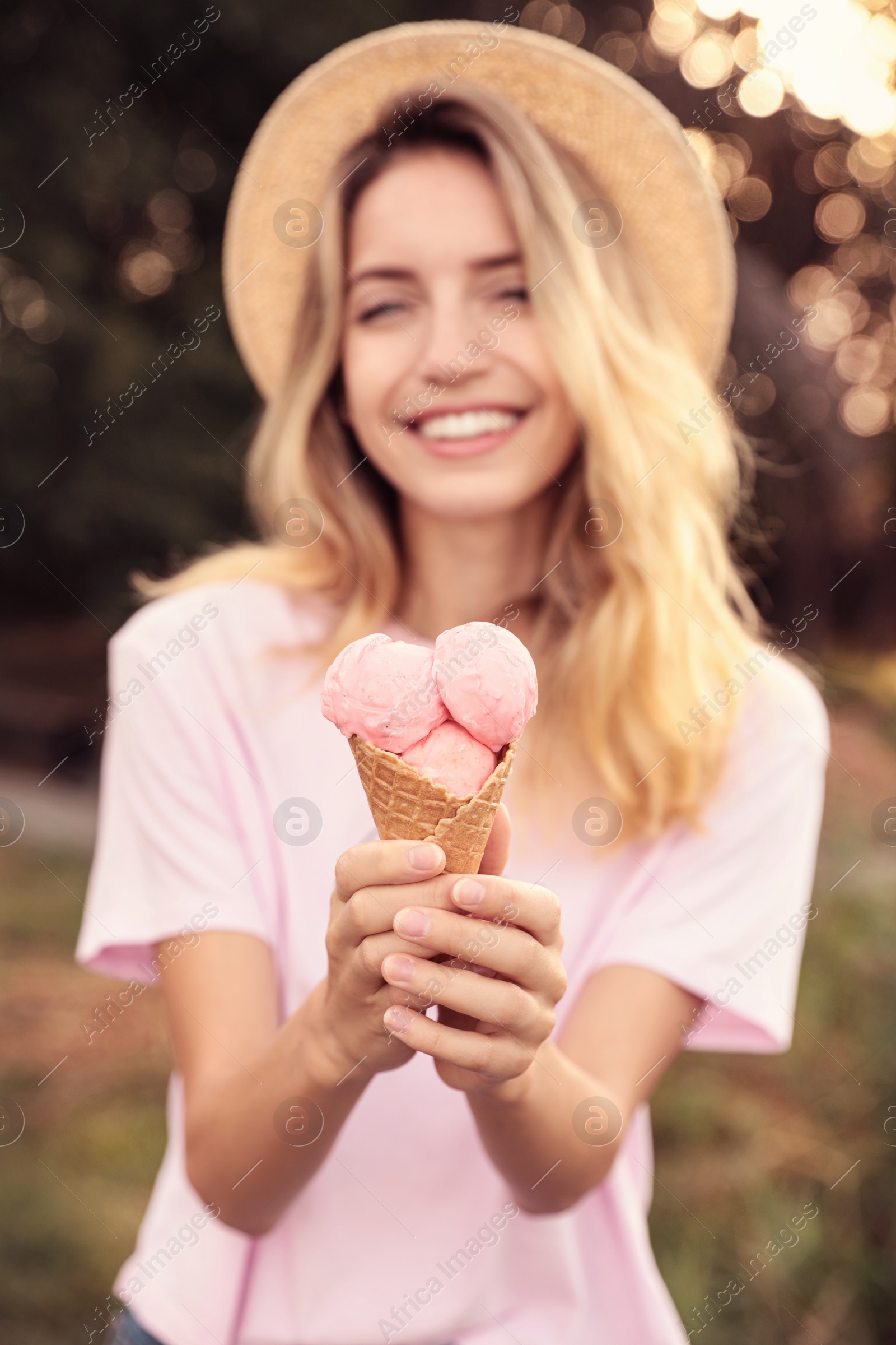 Photo of Happy young woman with delicious ice cream in waffle cone outdoors, focus on hand