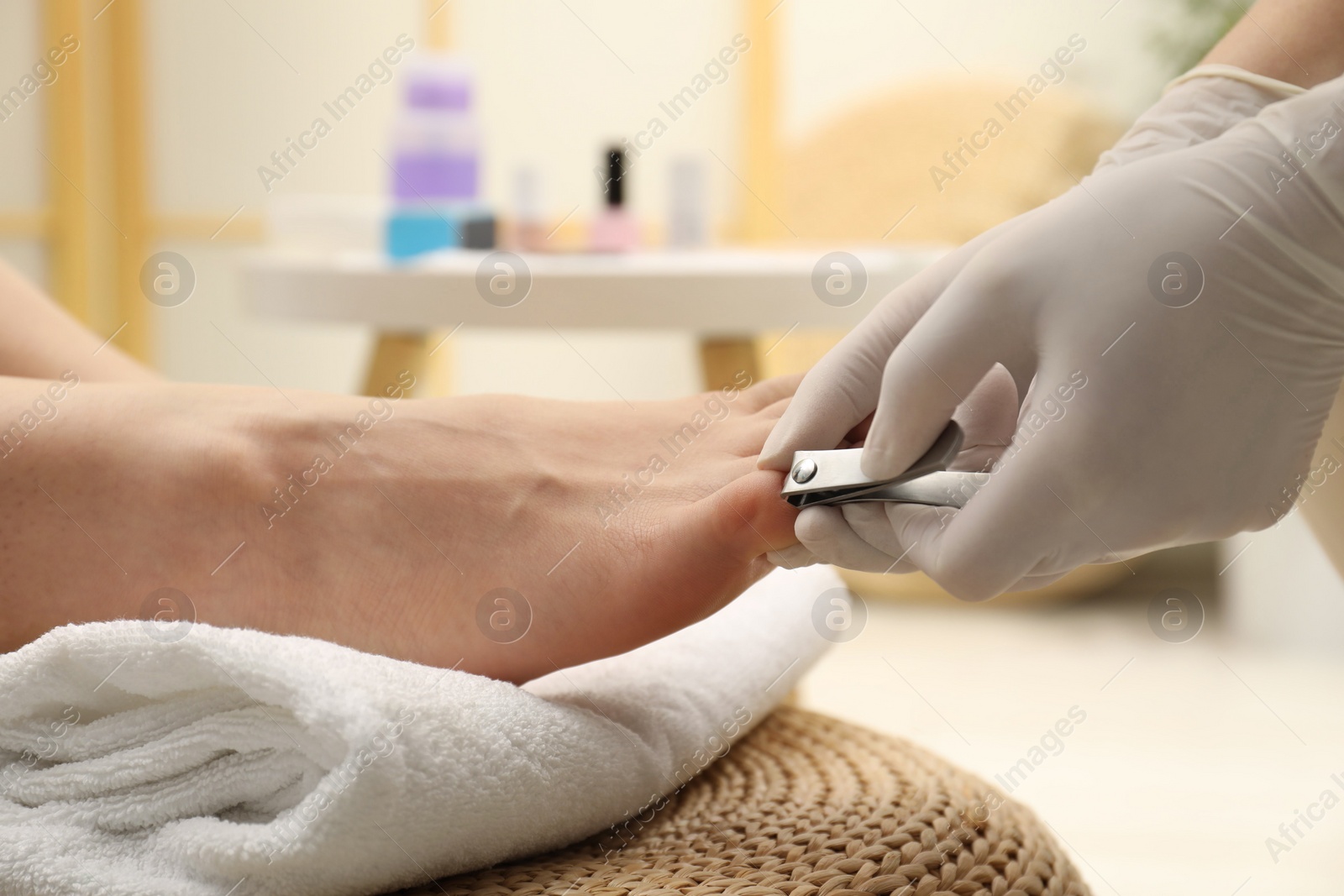 Photo of Professional pedicurist cutting client`s toenails with clipper in beauty salon, closeup