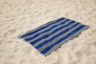 Photo of Grey and blue striped beach towel on sand