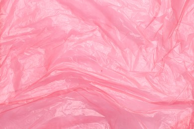 Photo of Crumpled pink plastic bag as background, top view