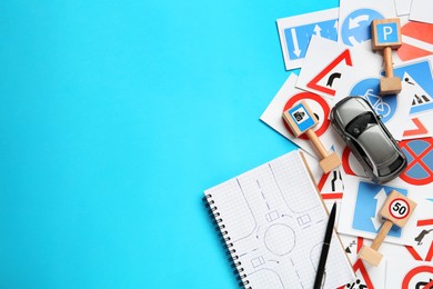 Photo of Many different road signs, notebook and toy car on light blue background, flat lay with space for text. Driving school