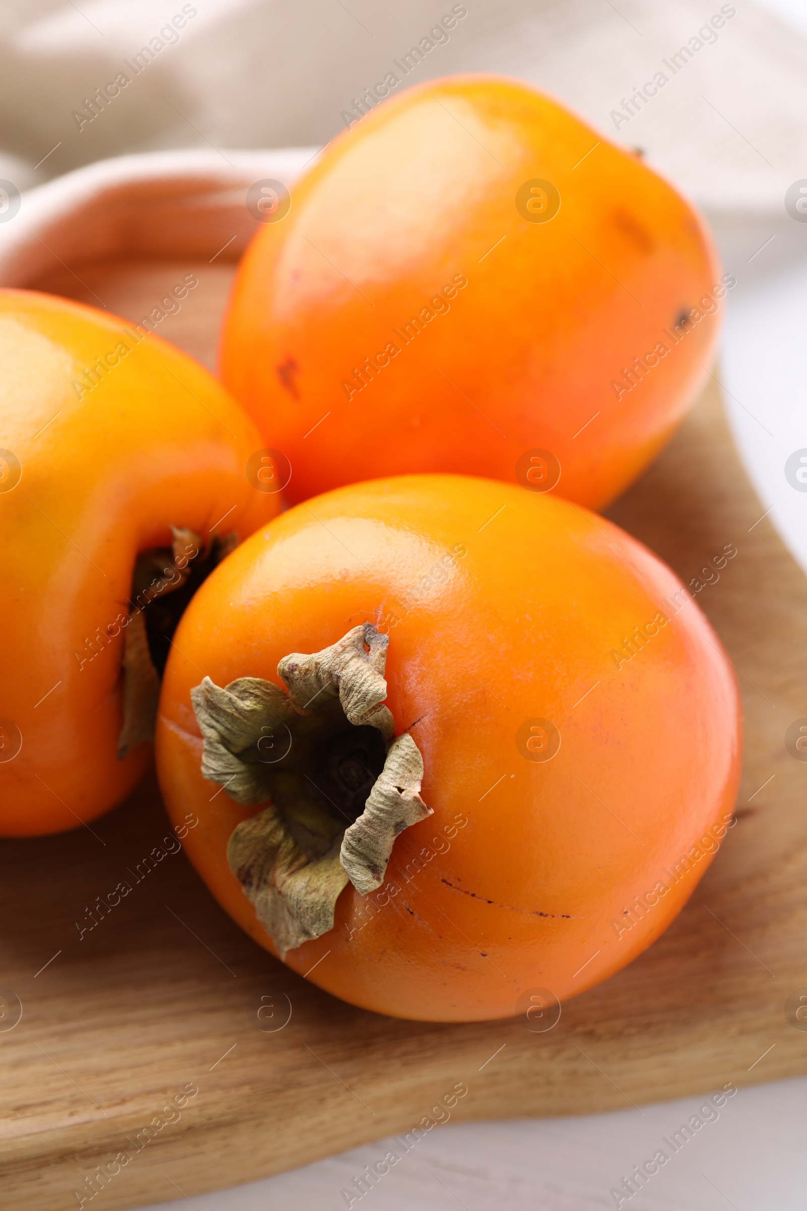 Photo of Board with delicious ripe persimmons on table, closeup