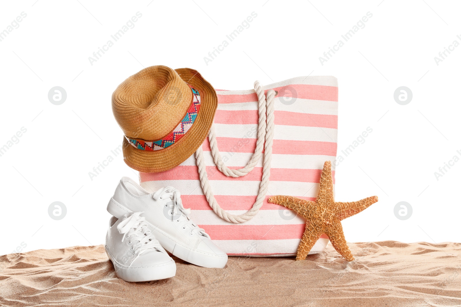 Photo of Stylish striped bag and beach accessories on sand against white background