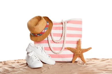 Photo of Stylish striped bag and beach accessories on sand against white background