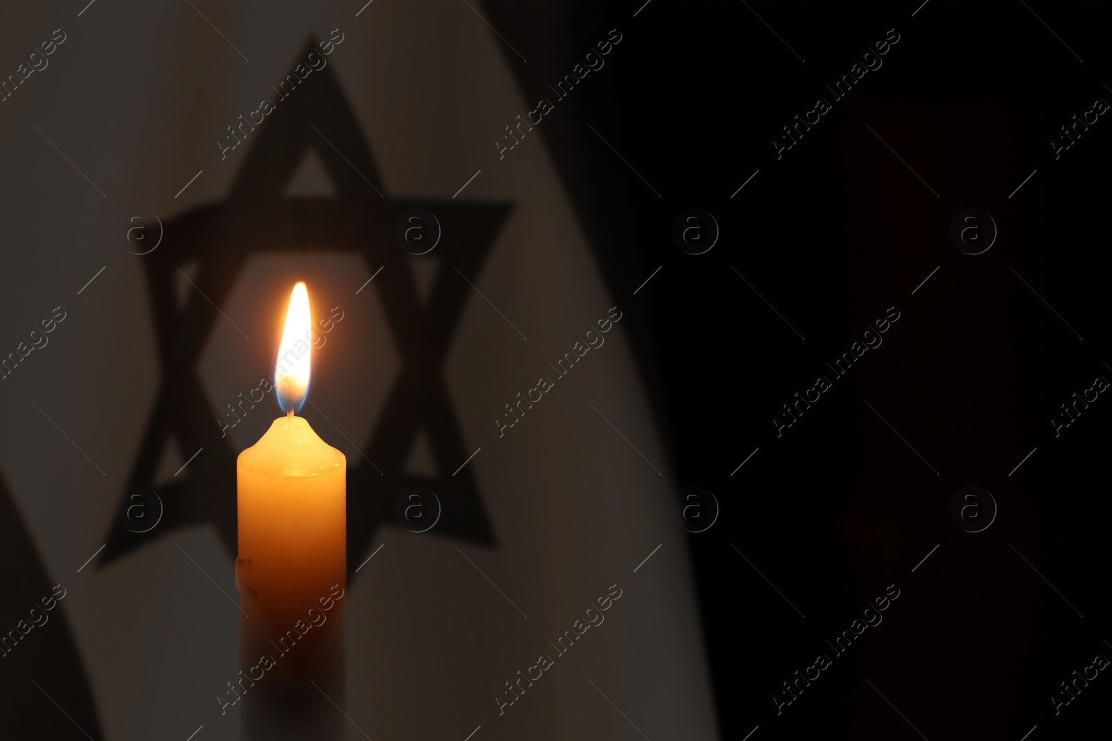 Image of Burning candle against flag of Israel on black background
