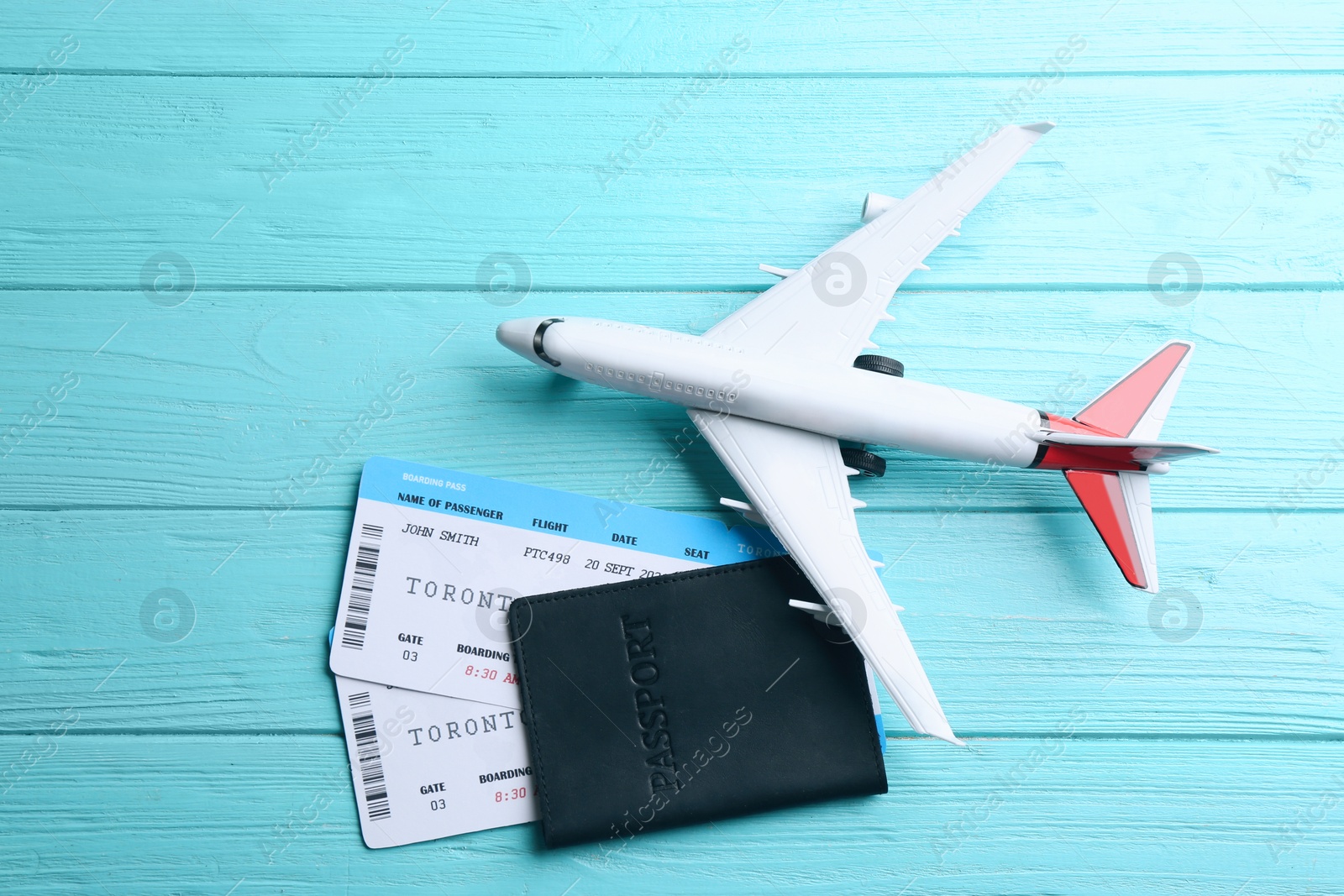 Photo of Toy airplane and passport with tickets on light blue wooden background, flat lay
