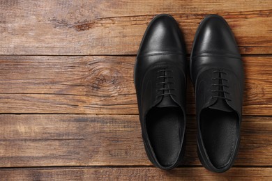 Photo of Pair of black leather men shoes on wooden background, top view. Space for text