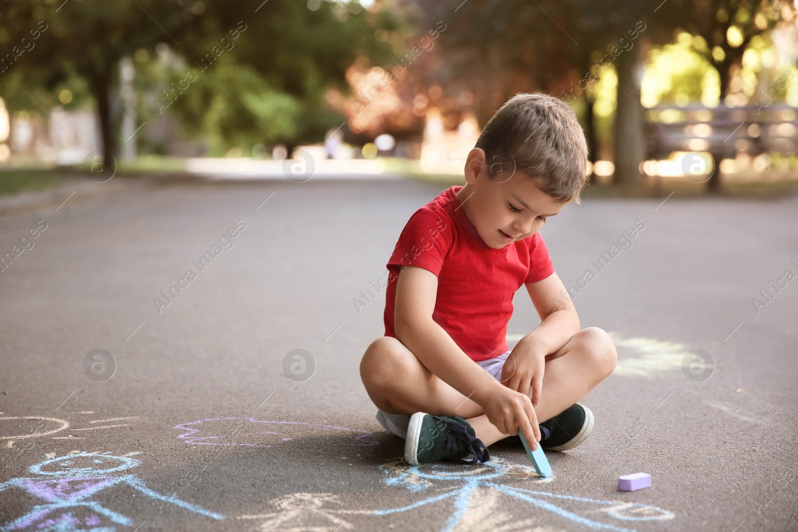 Photo of Little child drawing family with chalk on asphalt