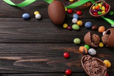 Tasty chocolate eggs and sweets on wooden table, space for text