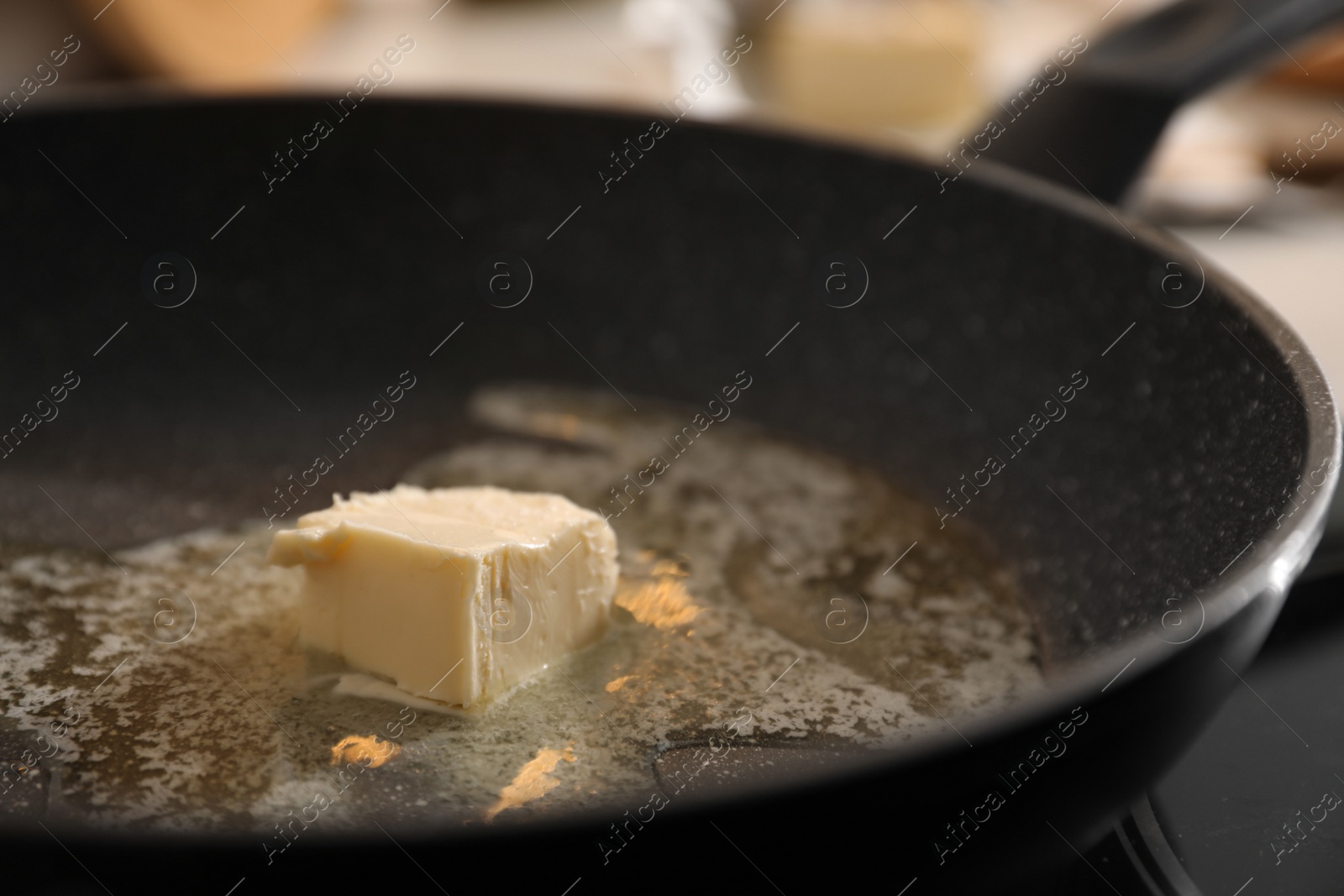 Photo of Frying pan with melted butter on stove, closeup