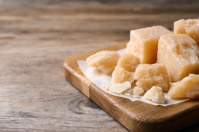 Pieces of delicious parmesan cheese on wooden table, closeup. Space for text