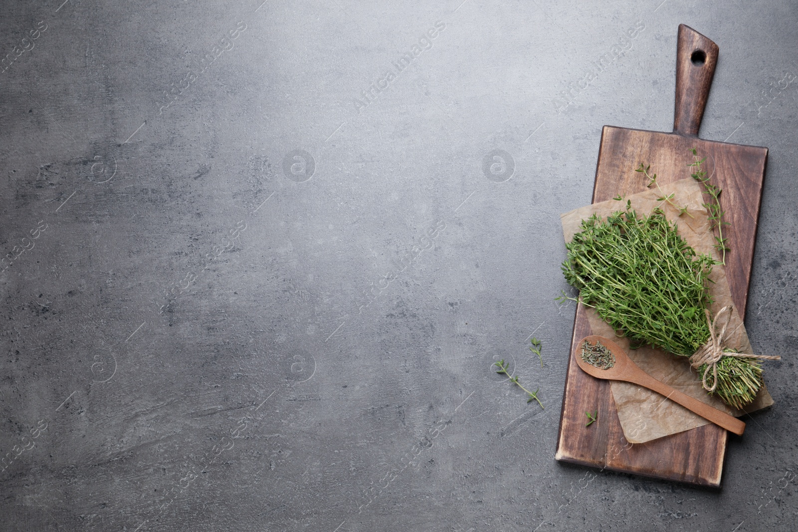 Photo of Bunch of aromatic thyme on grey table, top view. Space for text