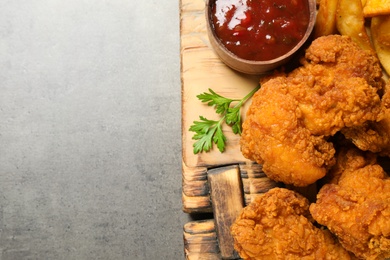 Photo of Tasty deep fried chicken pieces served on grey table, top view. Space for text