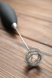 Photo of Black milk frother wand on wooden table, closeup