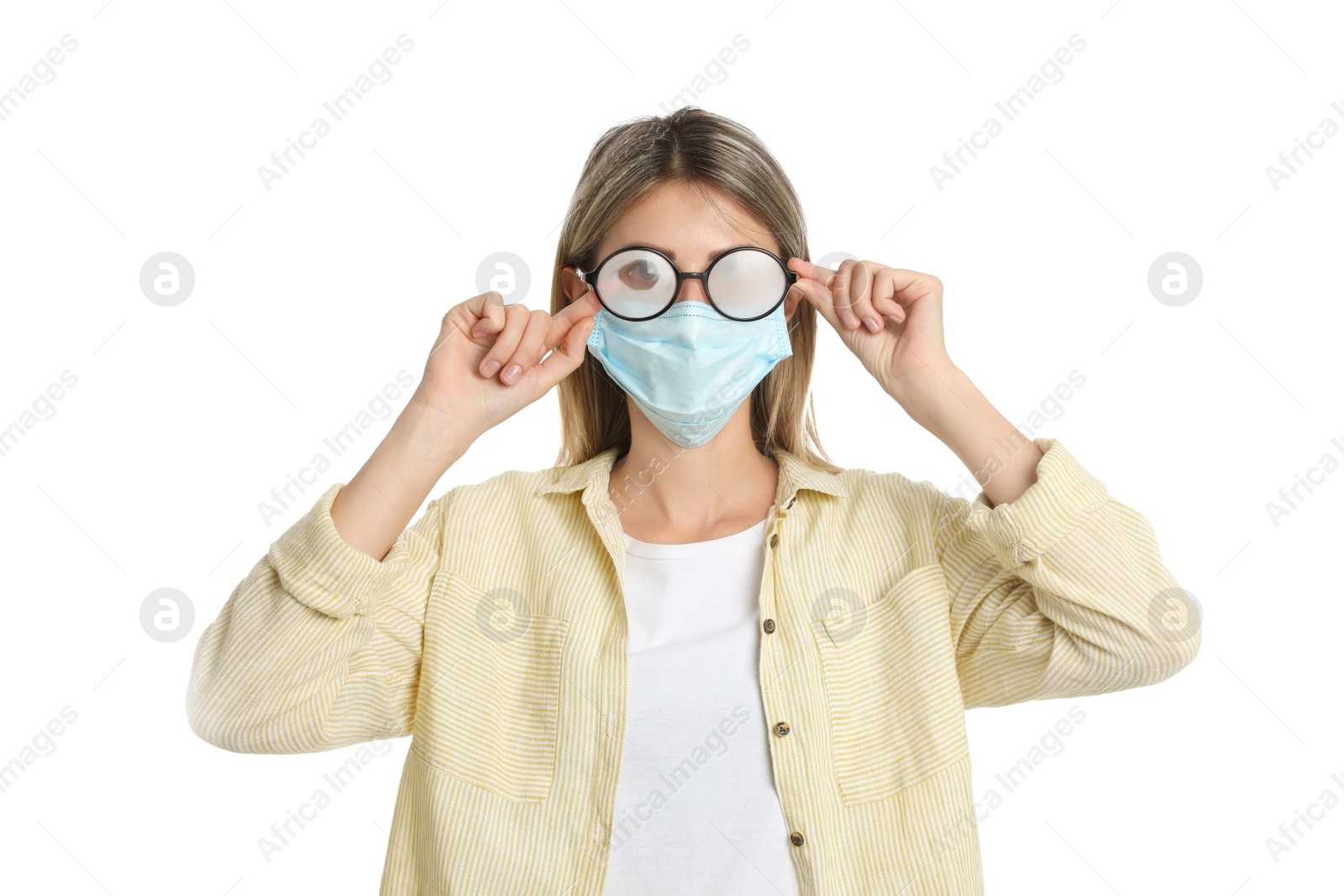 Photo of Woman wiping foggy glasses caused by wearing disposable mask on white background. Protective measure during coronavirus pandemic