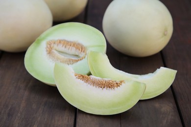 Photo of Tasty whole and cut ripe melons on wooden table