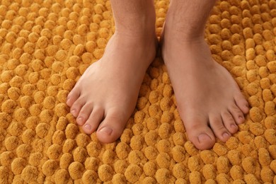 Photo of Man standing on soft orange bath mat, closeup