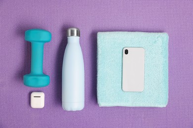 Photo of Flat lay composition with stylish thermo bottle and dumbbell on purple textured background