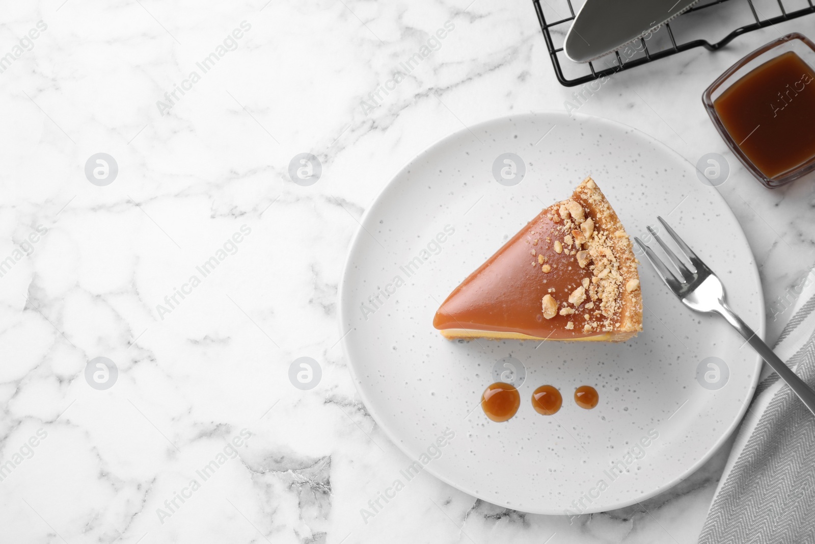 Photo of Piece of delicious cake with caramel served on white marble table, flat lay. Space for text