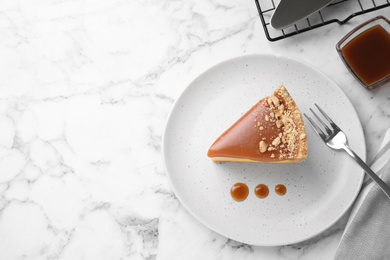 Photo of Piece of delicious cake with caramel served on white marble table, flat lay. Space for text