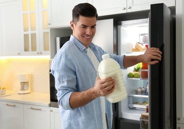 Photo of Man with gallon of milk near refrigerator in kitchen