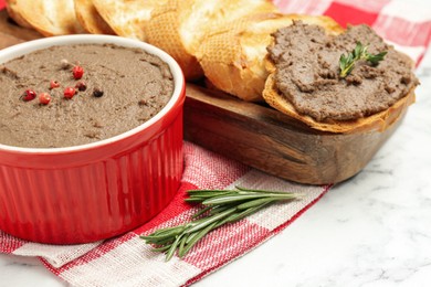 Photo of Tasty liver pate, rosemary and slices of bread on white marble table, closeup