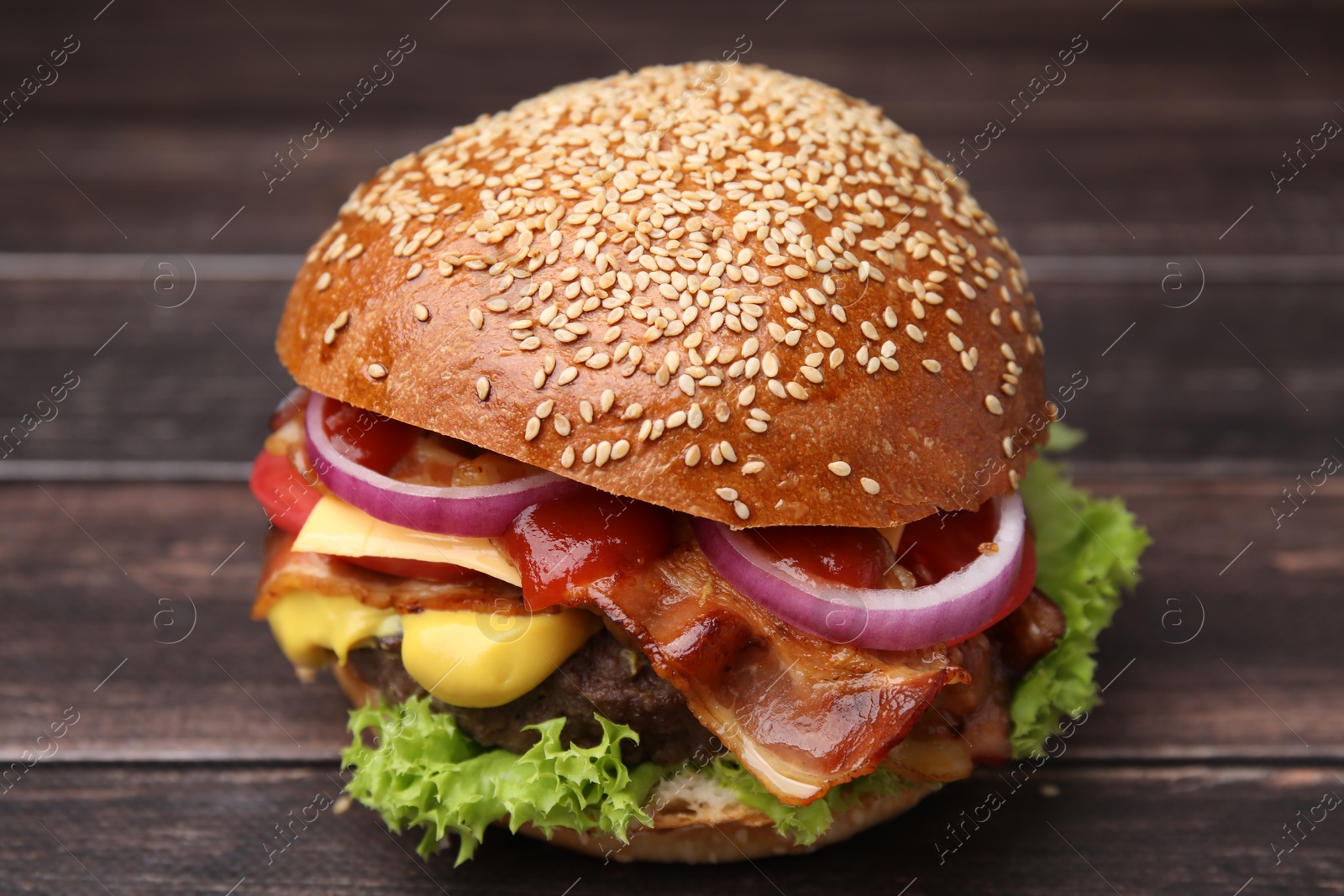 Photo of Delicious burger with bacon, patty and vegetables on wooden table, closeup