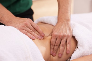 Photo of Woman receiving professional belly massage indoors, closeup