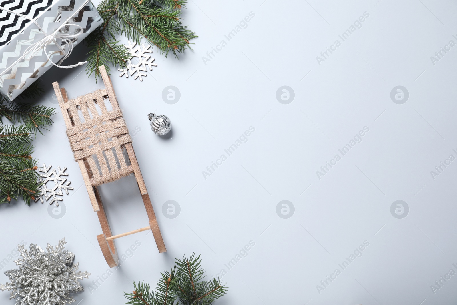 Photo of Flat lay composition with sleigh, Christmas decorations and fir tree branches on light background. Space for text