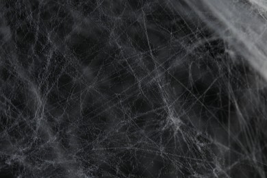 Photo of Creepy white cobweb on dark background, closeup