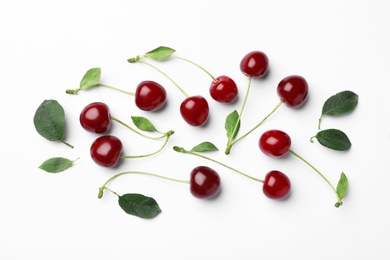 Tasty ripe cherries with leaves on white background, top view