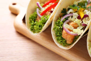 Photo of Delicious fish tacos served on wooden table, closeup