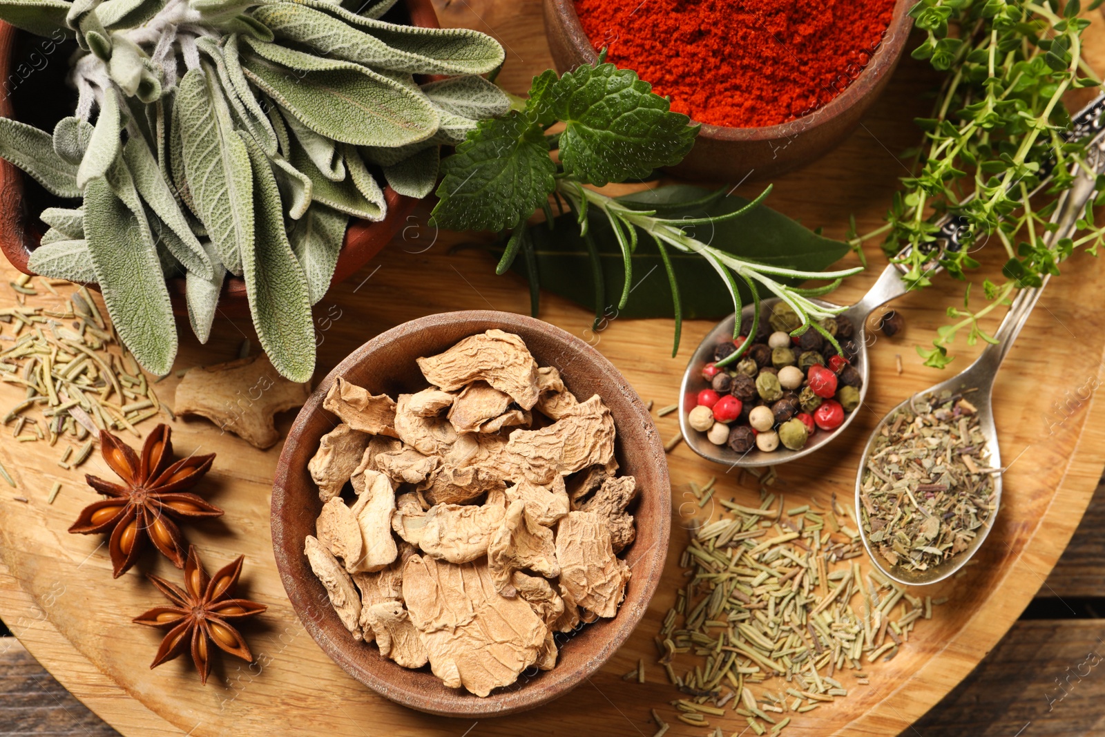 Photo of Different herbs and spices on wooden table, top view