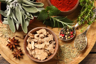 Photo of Different herbs and spices on wooden table, top view