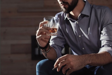 Photo of Man with glass of whiskey and cigar at home, closeup. Space for text