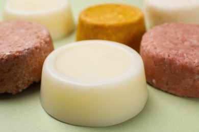 Photo of Group of solid shampoo bars on green table, closeup. Hair care