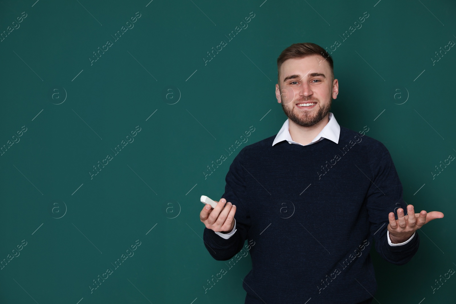 Photo of Portrait of young teacher with chalk on green background. Space for text